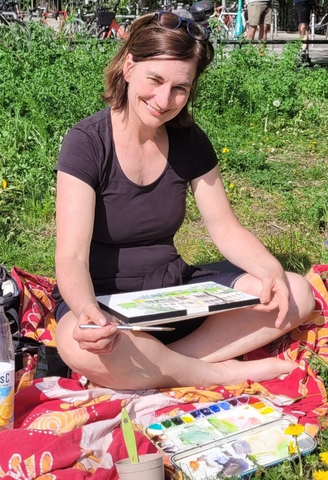 Ina malt drau&szlig;en im Gras, mit Skizzenbuch und Wasserfarbkasten